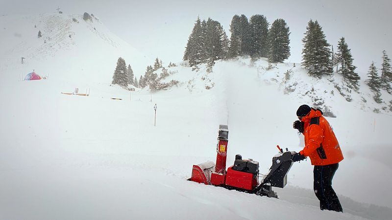 Worker clearing deep snow with a snowblower