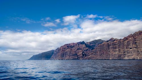 Free A stunning view of towering coastal cliffs against a bright blue sky and tranquil sea. Stock Photo