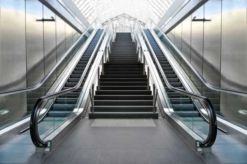 A futuristic indoor escalator and staircase with sleek, modern architecture.