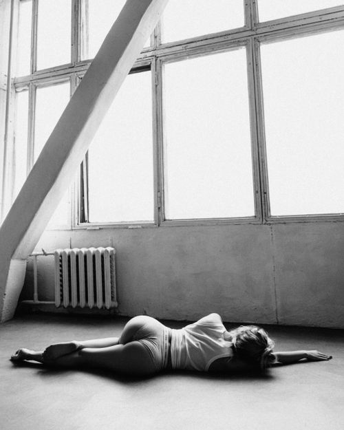 Free Artistic black and white photo of a woman lying in a studio with large windows. Stock Photo