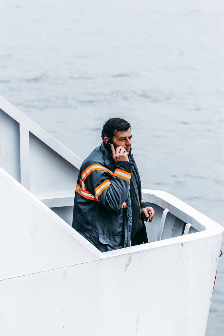 Man Answering Phone Call On Boat At Sea