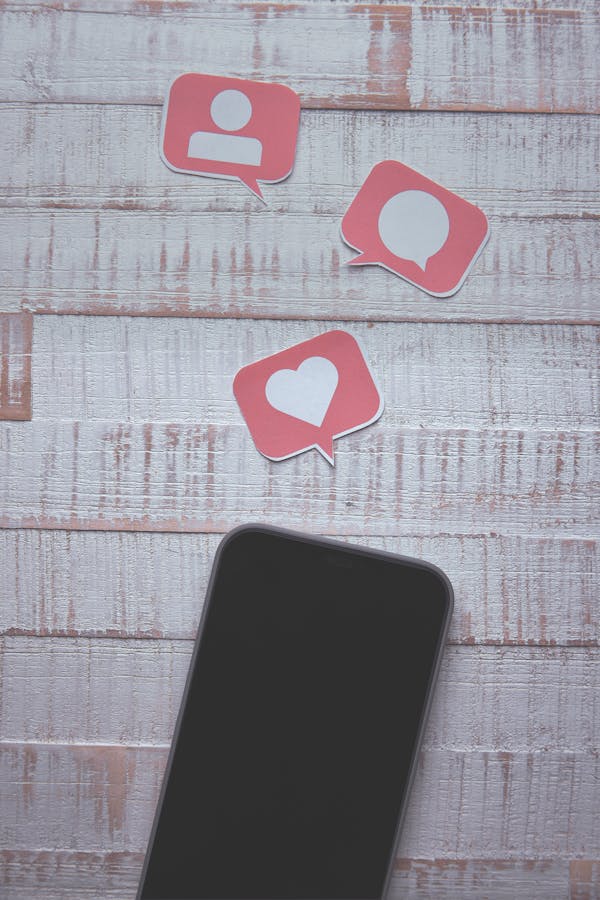 Picture of phone with symbols of hearts, comments and likes inside speech bubbles