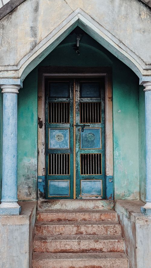Free Old blue door with stone steps and arched entrance, creating a vintage architectural scene. Stock Photo