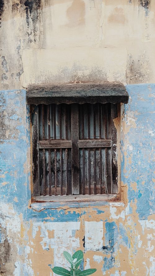 Free Aged wooden window set against a faded, colorful stucco wall. Stock Photo
