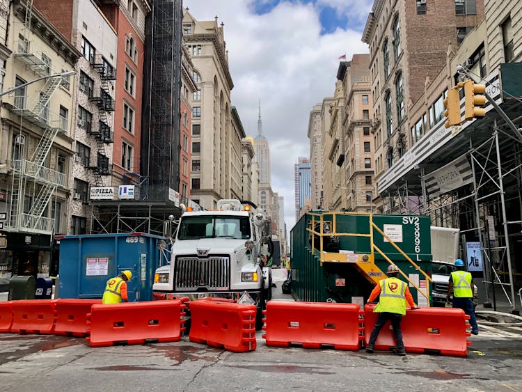 Workers And Truck Near Barriers On Street In City