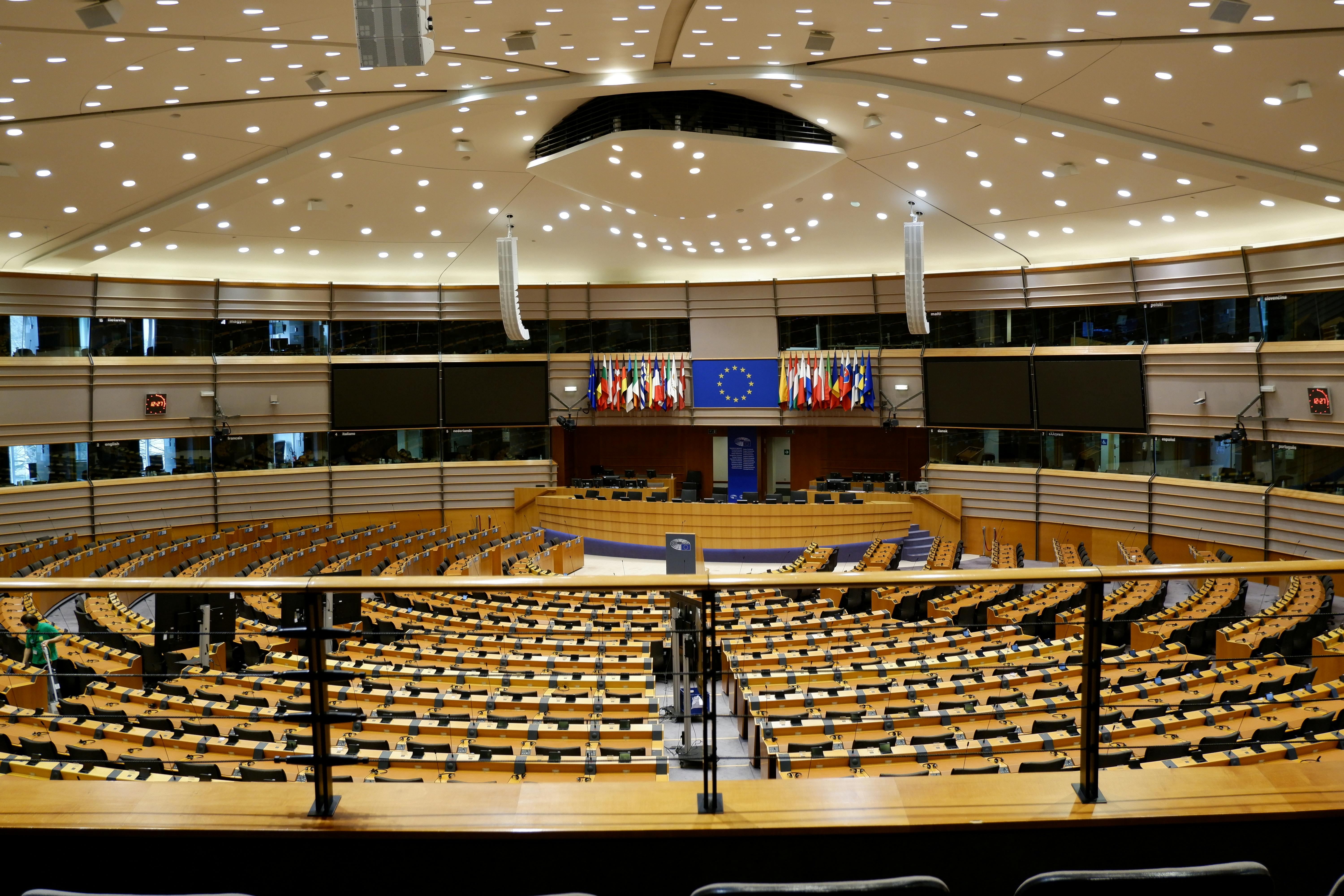 European Parliament chamber with curved rows of seats, a central podium and EU member state flags