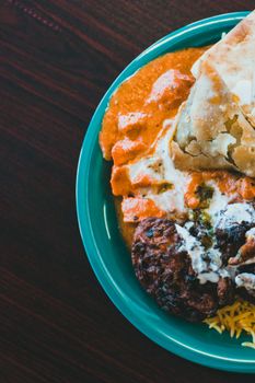 Close-up of a vibrant plate with Indian dishes including samosa and curry, offering a rich taste experience.