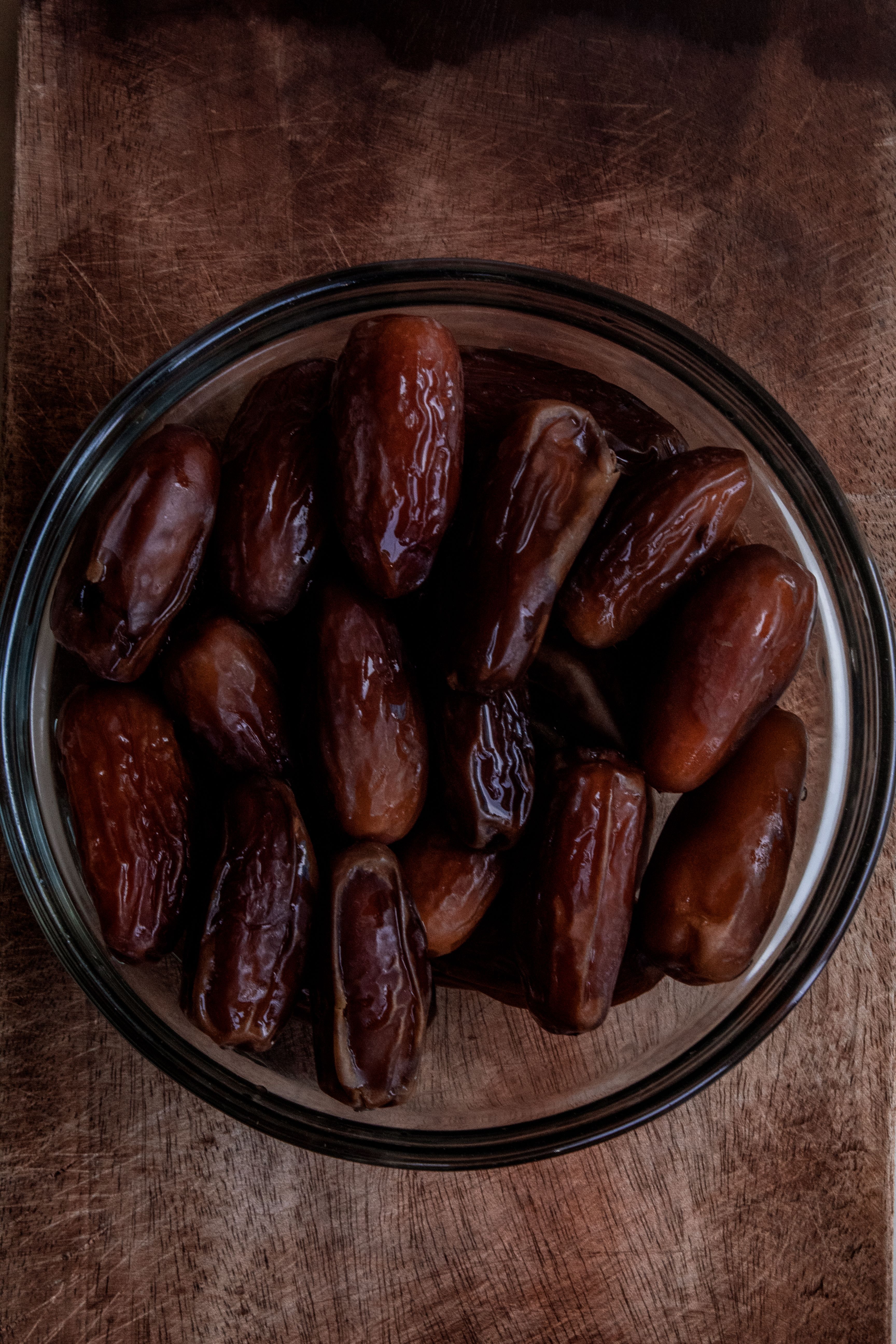 A bowl of fresh Medjool dates on a rustic wooden surface, perfect for healthy snacks.