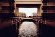 现代建筑结构横跨平静的城市运河，由建筑物和树木构成