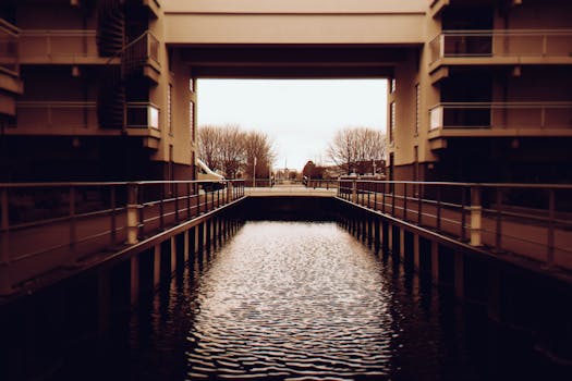 现代建筑结构横跨平静的城市运河，由建筑物和树木构成