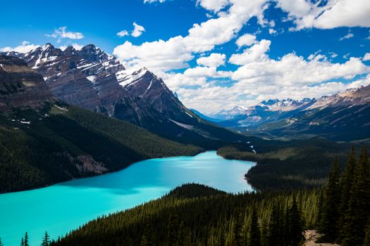 Breathtaking mountain landscape with turquoise lake beneath a blue sky and scattered clouds.