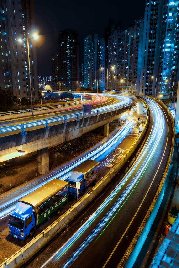 Illuminated City With Trucks On Elevated Roads At Night