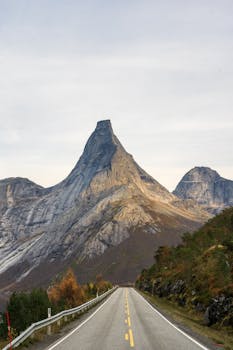 A scenic road leading to dramatic mountain peaks under a clear sky.