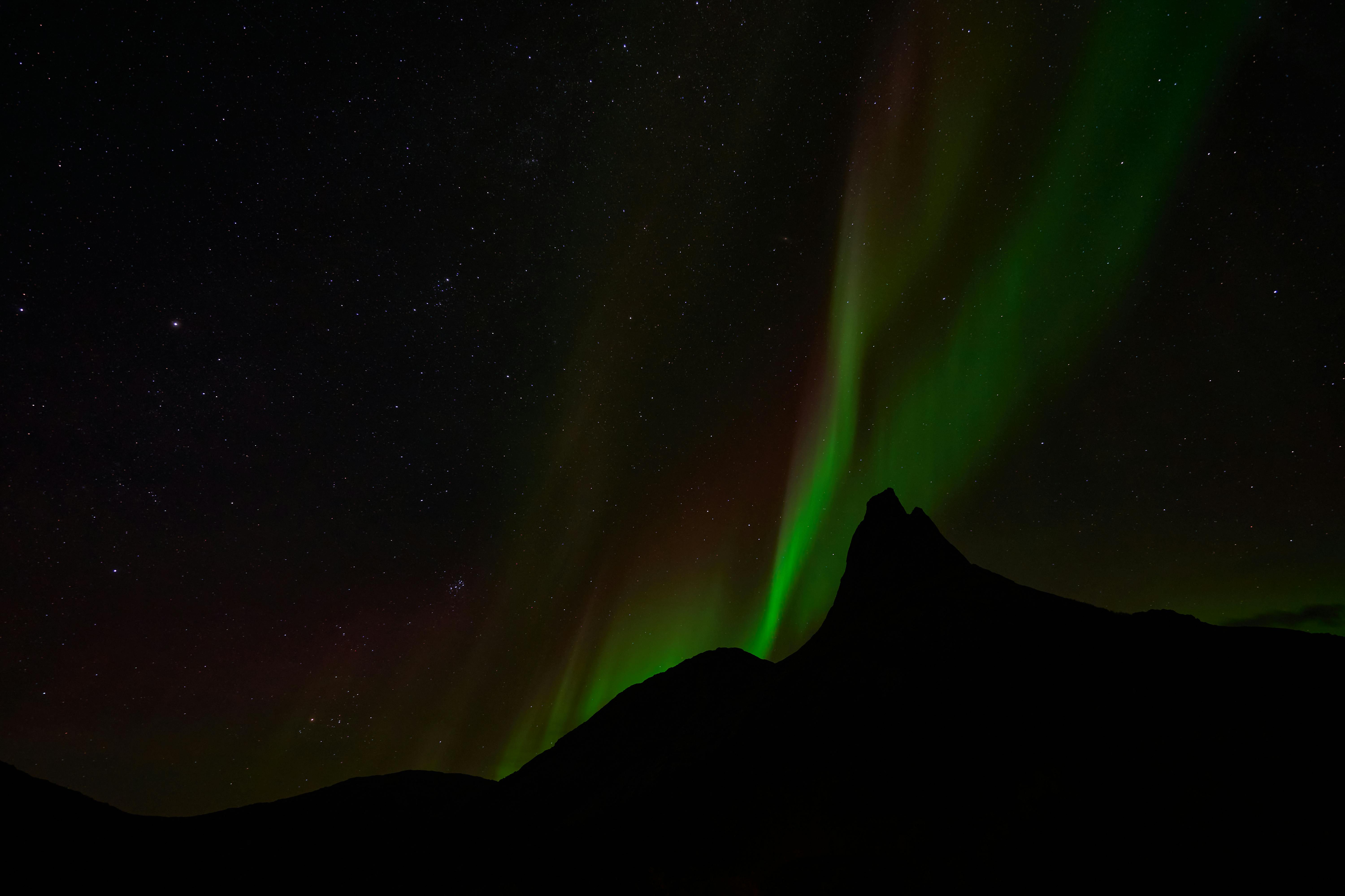 silhouette of mountain under northern lights