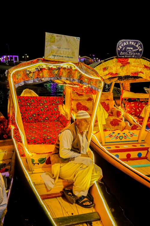 Free A man sits on a brightly decorated shikara boat on Dal Lake at night, Kashmir, India. Stock Photo