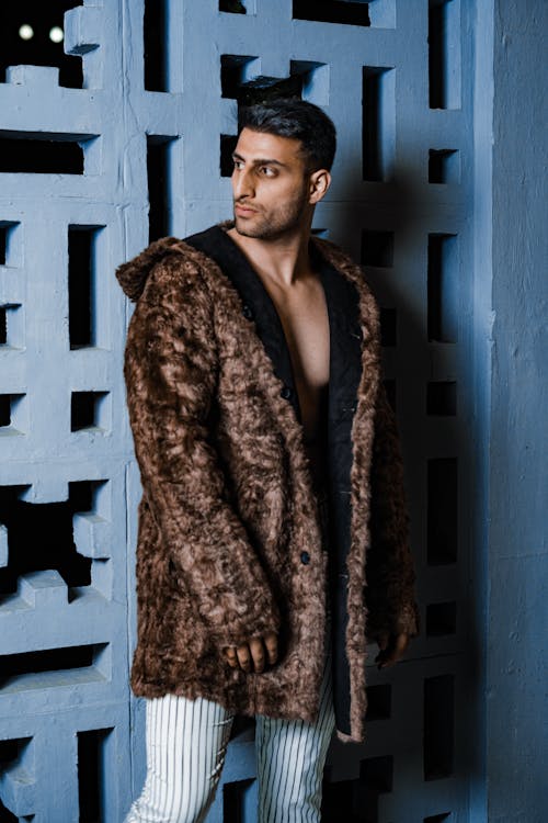 Man in Brown Fur Coat Near Concrete Wall