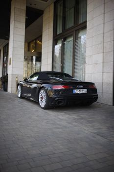 Sleek black sports car parked outside a modern building, emphasizing luxury and style.