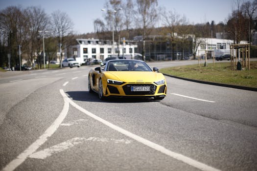 A yellow sports car cruising down an open road on a sunny day, showcasing luxury and performance.
