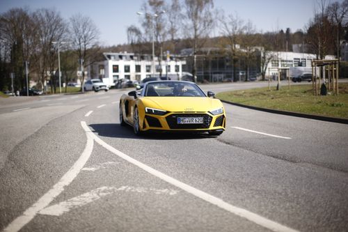 Free A yellow sports car cruising down an open road on a sunny day, showcasing luxury and performance. Stock Photo