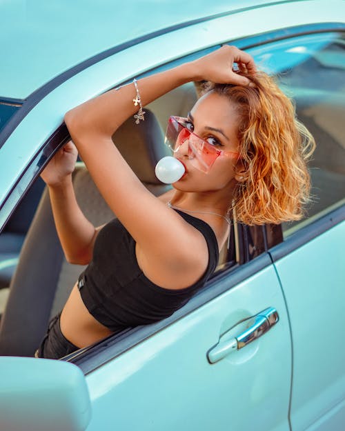 Woman Sitting in Car Making Bubble out of Gum