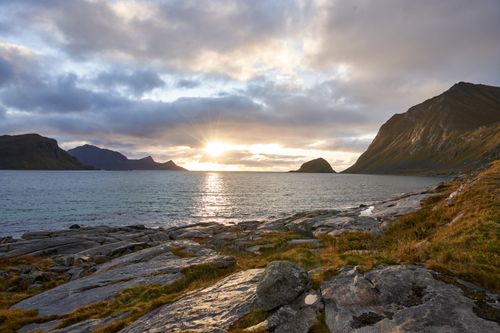 Free Sunset view of a rocky coast with mountains and sea, capturing nature's beauty and tranquility. Stock Photo
