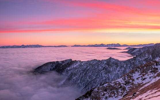 Breathtaking sunrise over snow-covered mountains with a sea of clouds below, capturing nature's beauty.