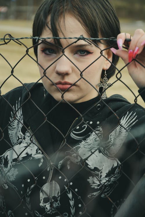 Free Close Up Photo of Woman Standing Behind Chain Link Fence Stock Photo