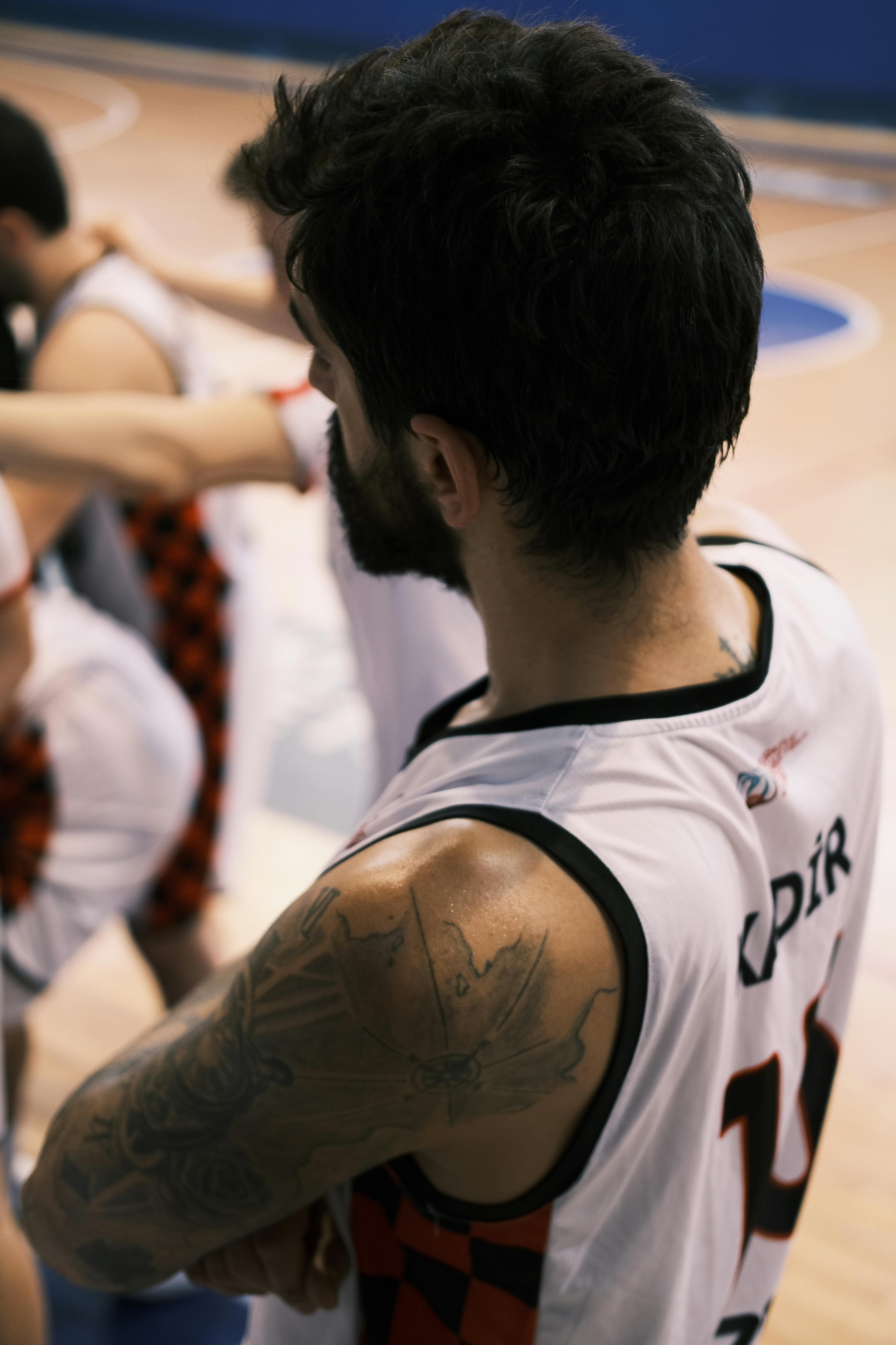 Athlete in a basketball jersey during a game indoors, showcasing focus and determination.