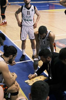 Basketball team and coach strategizing on court during a game timeout in Türkiye.
