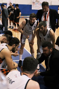 Basketball players and coach strategizing during a game huddle on the court.