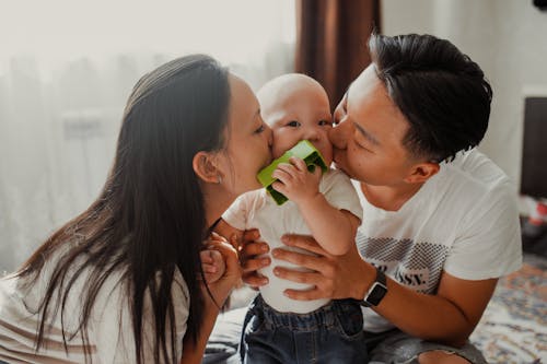 Free Woman in White Shirt Kissing Baby in White Shirt Stock Photo