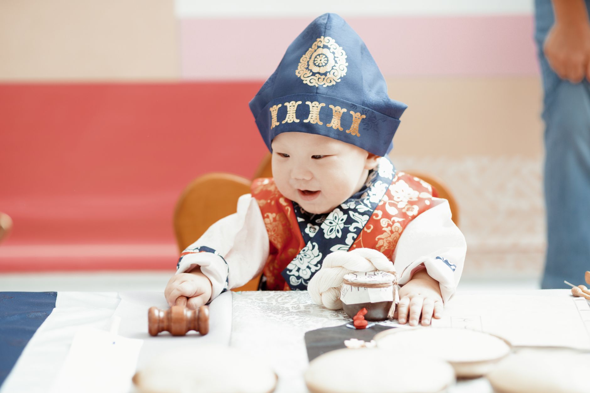 Cute Asian toddler in traditional attire playing at a table, indoors close-up.