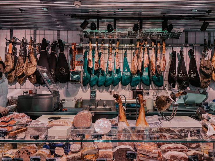 Cured meats hanging at a delicatessen counter — Julia R on Pexels