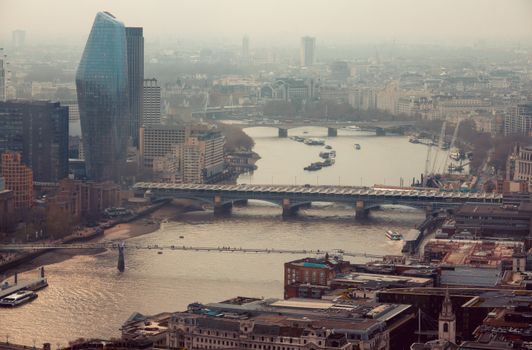 Aerial view of London's cityscape featuring Thames River and iconic skyscrapers.
