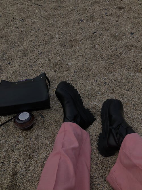 Free Person Wearing Pink Pants and Black Shoes Near Black Bag Stock Photo