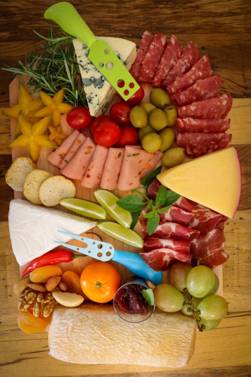 Free Top view of a vibrant charcuterie board with cheese, meats, fruits, and garnishes, perfect for appetizers. Stock Photo