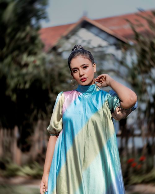 Free Outdoor portrait of a stylish woman in a colorful dress by a rustic house. Stock Photo