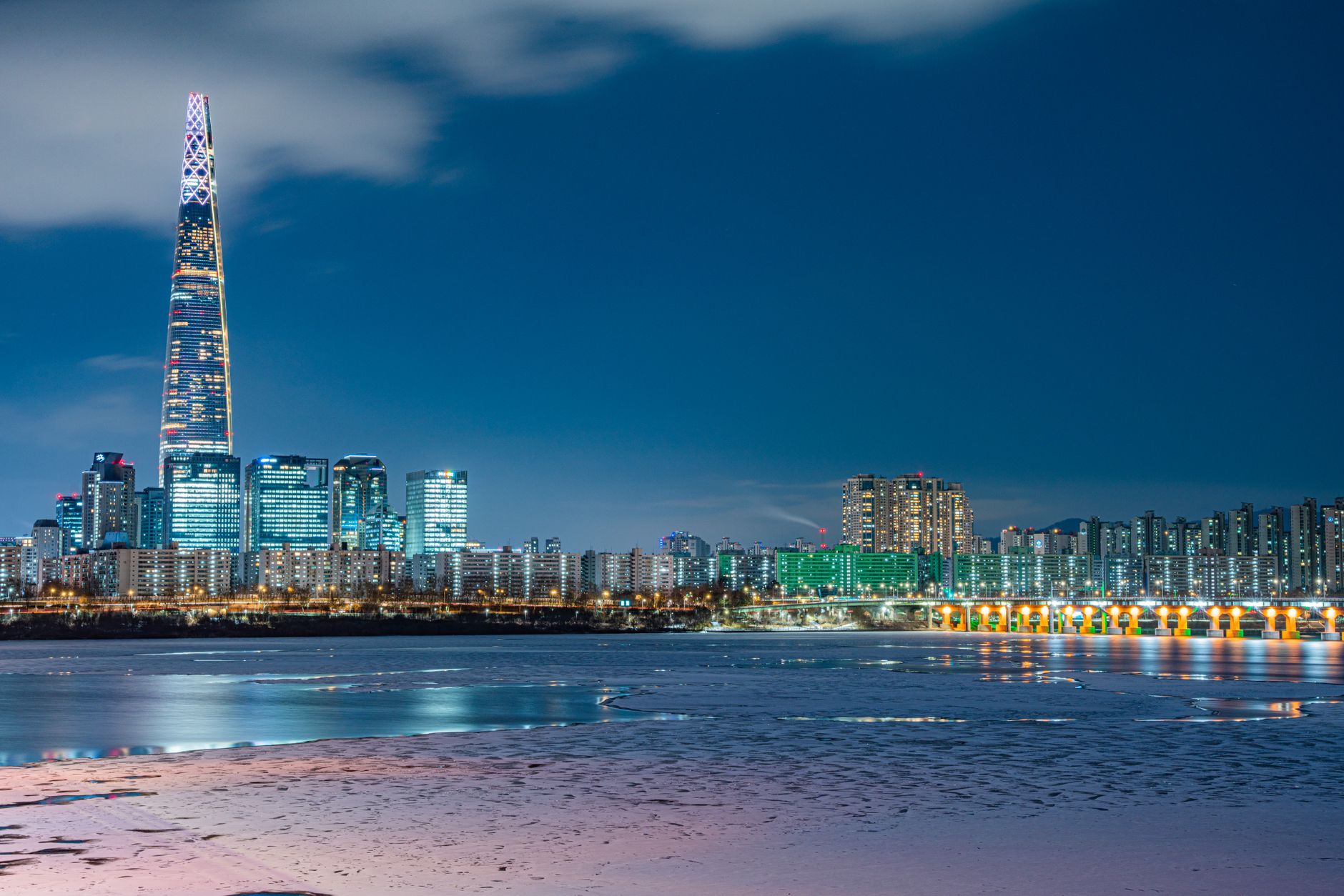 Stunning night view of Seoul featuring Lotte Tower and city skyline reflected on waterfront.
