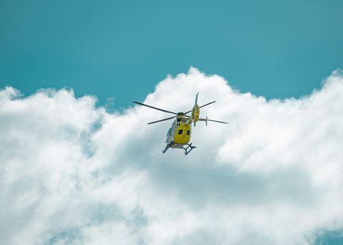 Free A yellow helicopter flying through white clouds against a blue sky, captured in La Coruña, Spain. Stock Photo