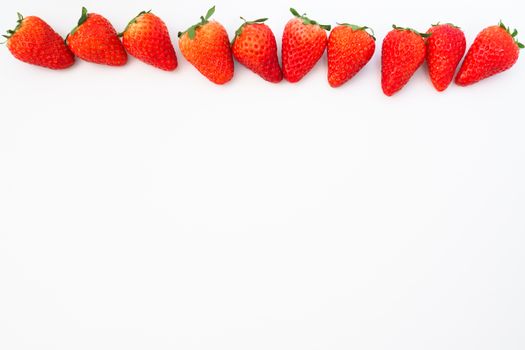 A row of ripe strawberries arranged on a white background, highlighting their vibrant red color.