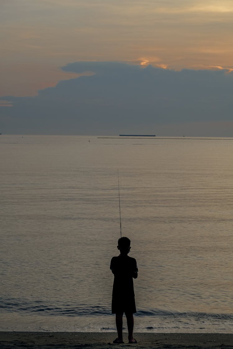 Silhouette Of A Child Fishing While On Shore