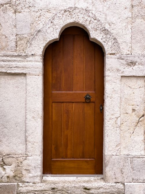 Free A rustic wooden door set in an ancient stone archway, perfect for architectural themes. Stock Photo