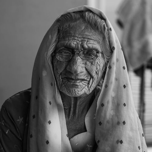 Free A black and white portrait of an elderly woman wearing glasses and a headscarf. Stock Photo