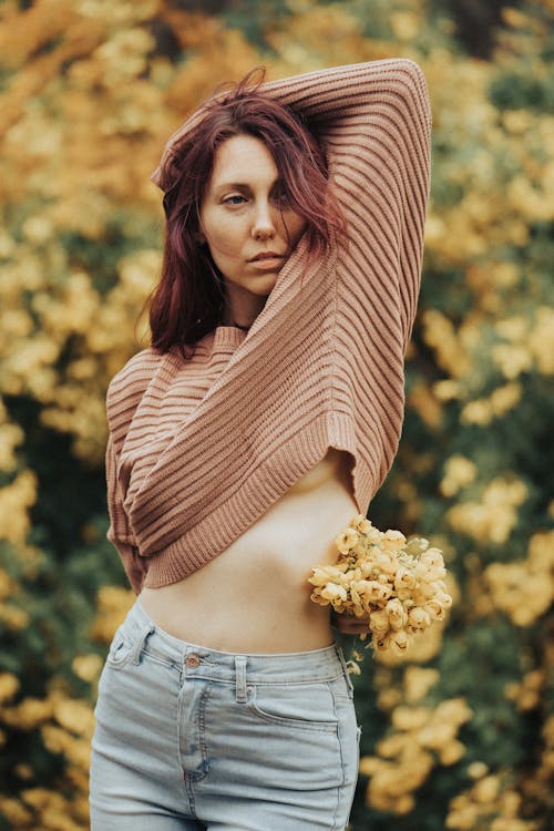 A Woman in Brown Knitted Sweater Holding Flowers