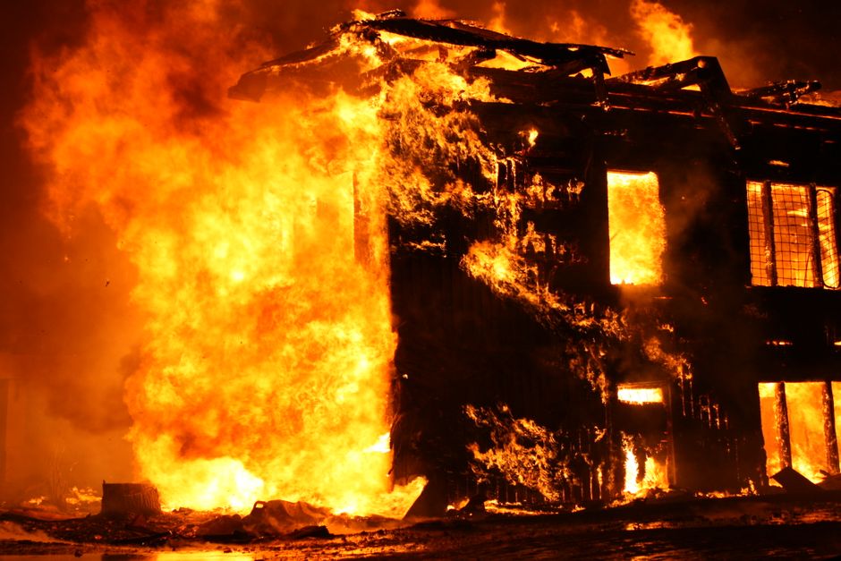 Intense flames consume a building in a dramatic nighttime fire scene.