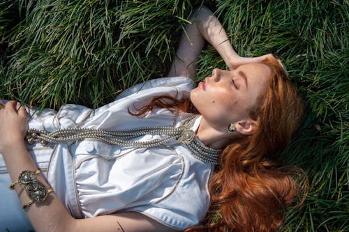 Free Top View of Redhead Woman with Eyes Closed Lying on Grass Stock Photo