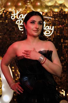 A woman in a stylish black dress celebrates a birthday indoors.