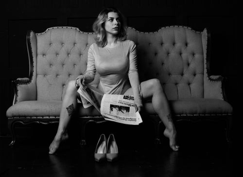 Free Stylish black and white portrait of a woman sitting on a sofa holding a newspaper. Stock Photo