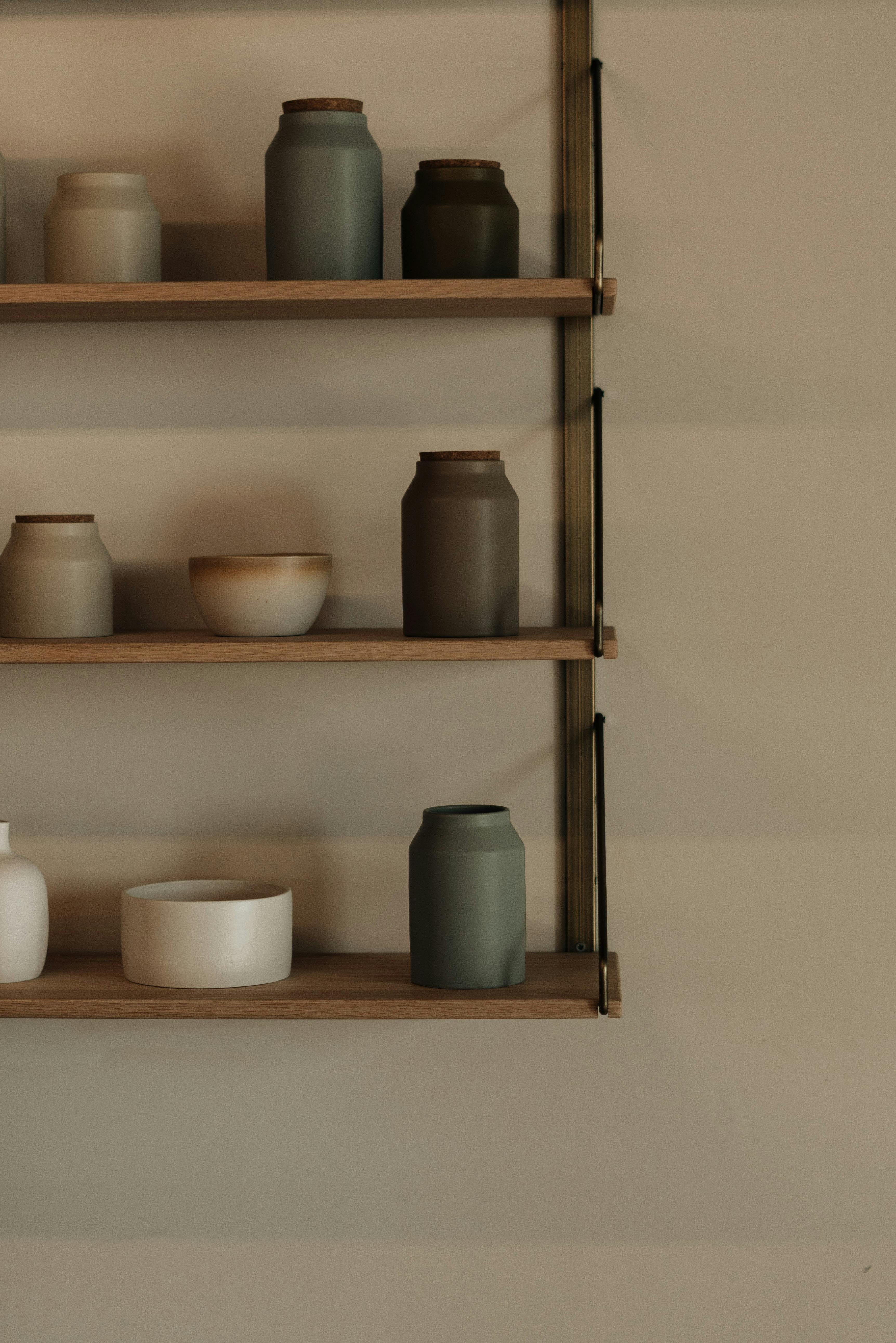 Stylish ceramic jars arranged on a rustic wooden shelf, evoking minimalist charm.