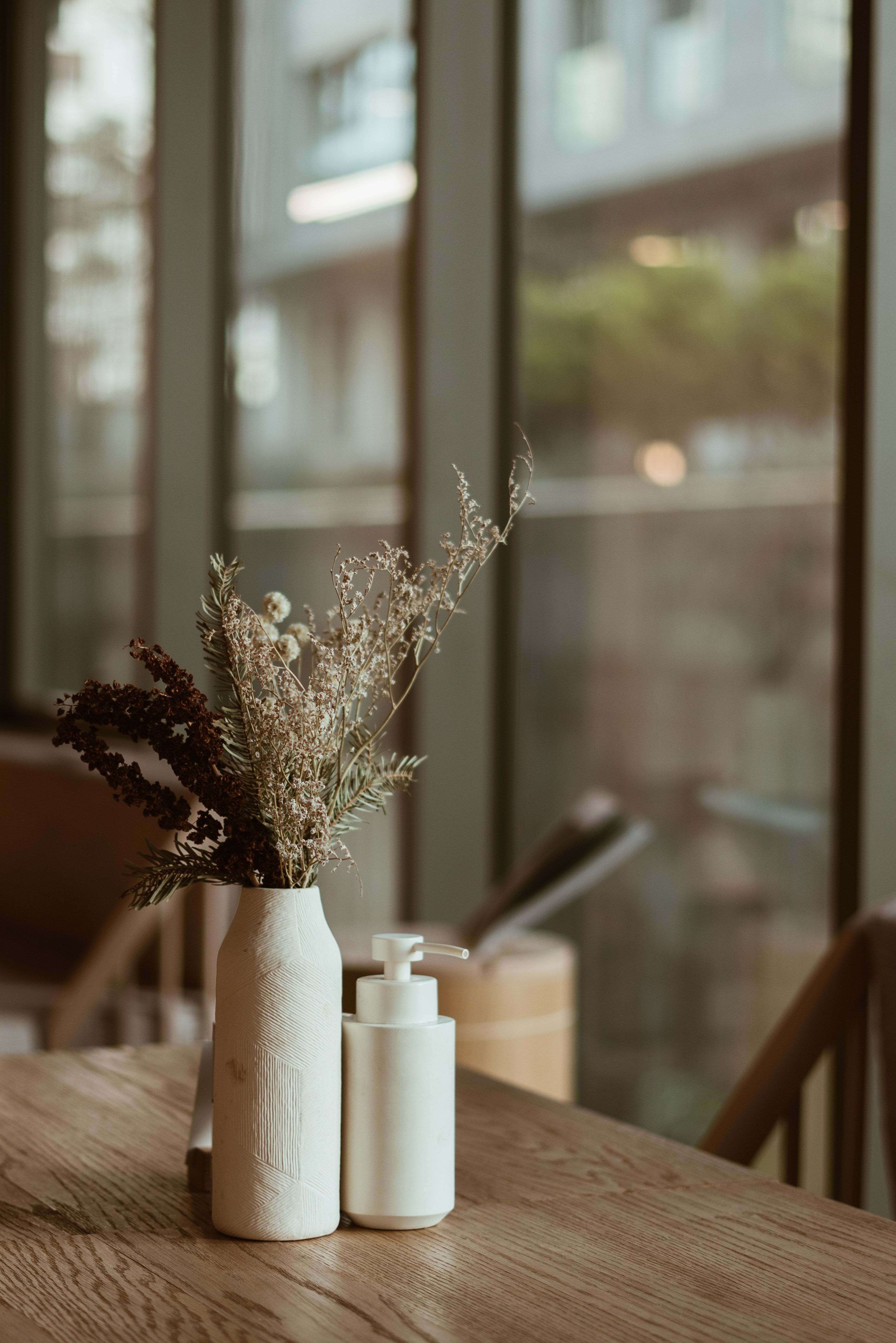A rustic floral arrangement in a vase sits by a window in an Istanbul cafe, offering a cozy atmosphere.